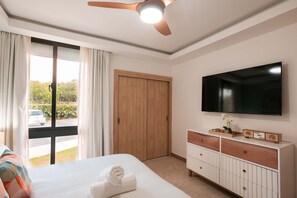 Ein Hotelzimmer mit Bett, Fernseher, Holzschrank und Blick ins Freie.