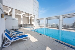 Ein Pool auf dem Dach mit Liegestühlen und Blick auf die Stadtlandschaft.