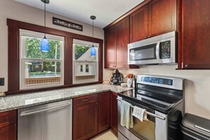 A kitchen with wooden cabinets, a stainless steel dishwasher, a microwave, and an oven. - Sleeps 7,  2BR-2BA | 5 mins walk to ISU (Ames)