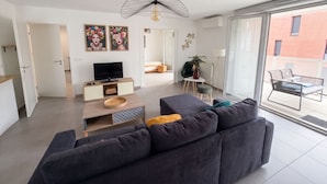 A modern living room with a sofa, TV, and artwork. - L Azulejo - Work From Home Ideal - Mobility Lease Rental - 4pax (Toulouse)