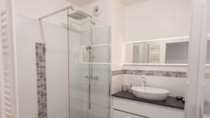 A modern bathroom with a glass-enclosed shower, a white sink, and a tiled backsplash. - L Azulejo - Work From Home Ideal - Mobility Lease Rental - 4pax (Toulouse)