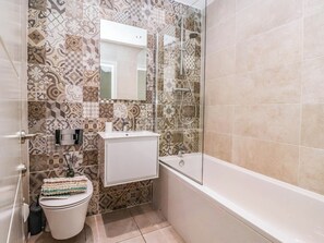 A bathroom with patterned tiles, a toilet, a sink, and a bathtub. - Blanket Row (Hull)