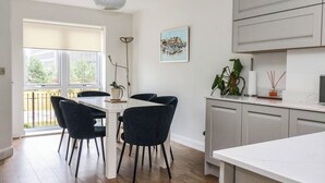 A modern kitchen with a dining area, wooden flooring, and a view through the window. - Blanket Row (Hull)