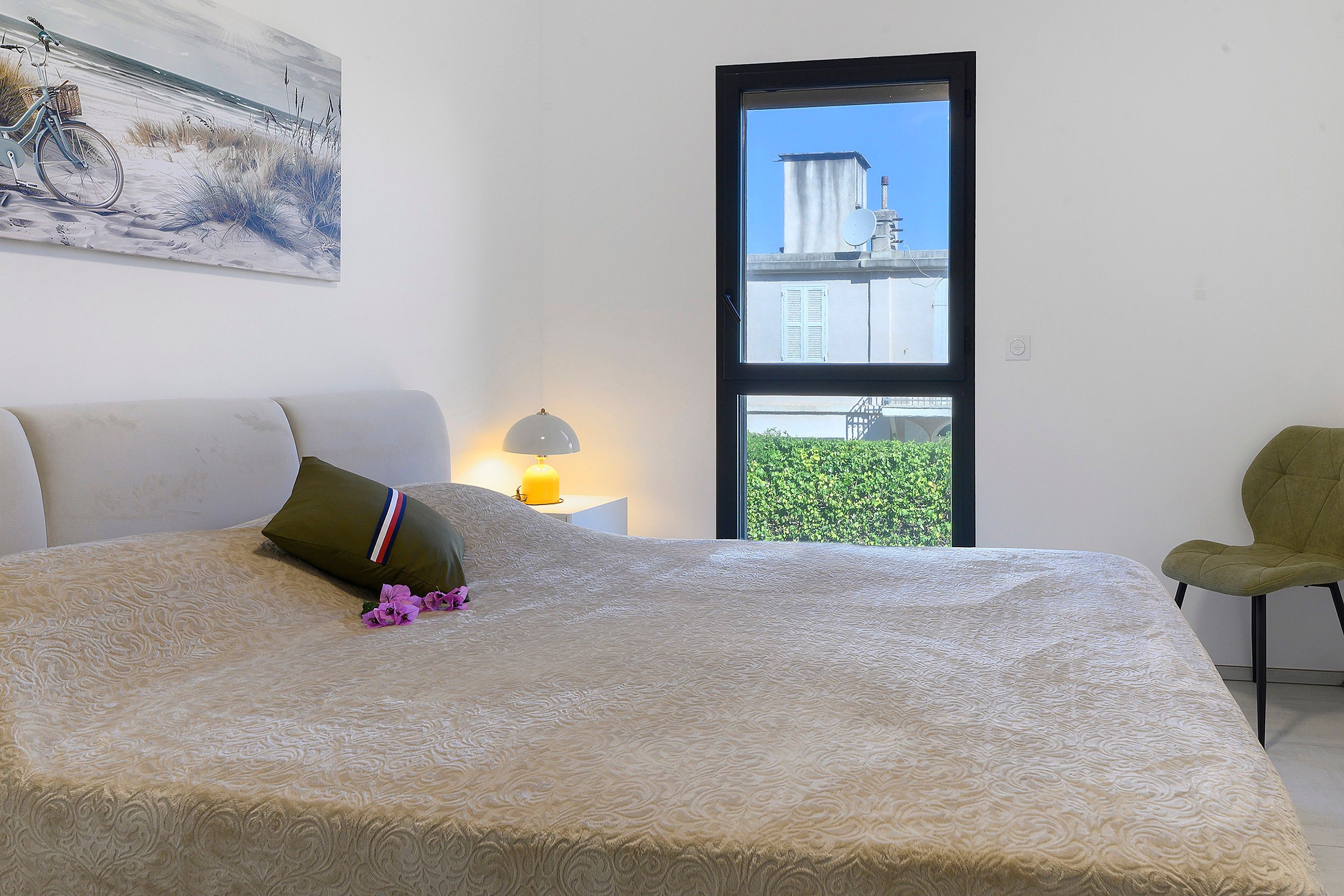 Une chambre à coucher avec un lit, une chaise, une fenêtre et un tableau accroché au mur.