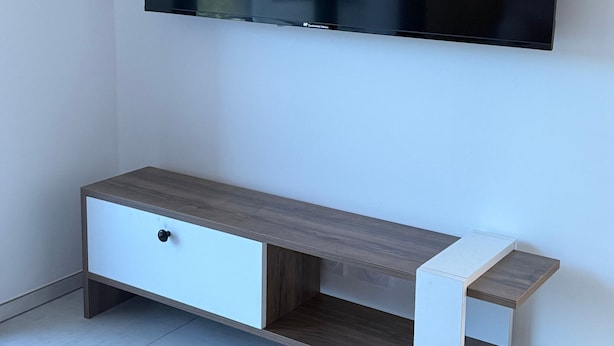 A flat-screen TV mounted on a wall above a wooden console with drawers.