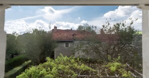 A rustic building with a red-tiled roof, surrounded by greenery and trees.