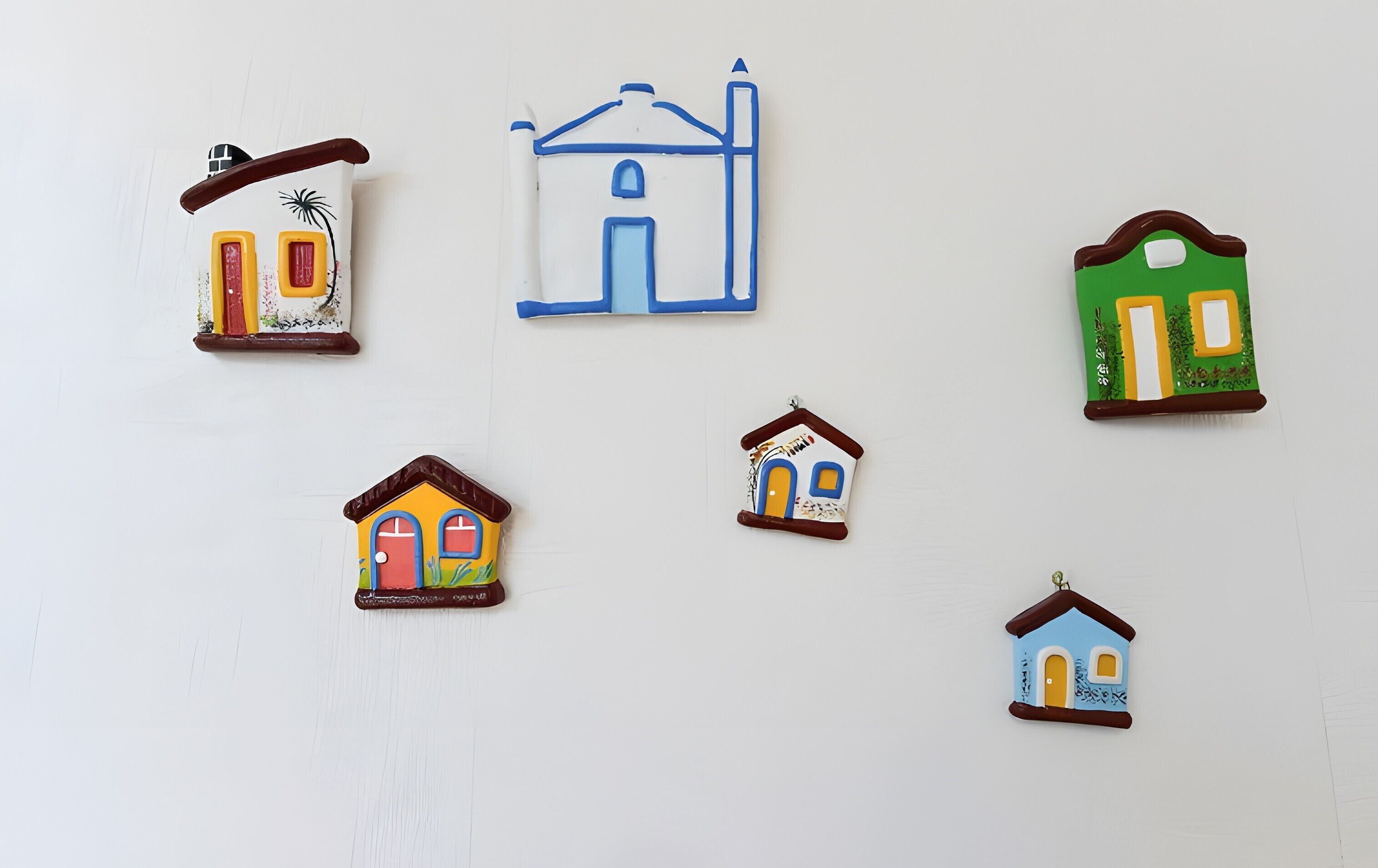 Een aantal decoraties in de vorm van huizen aan een muur.
