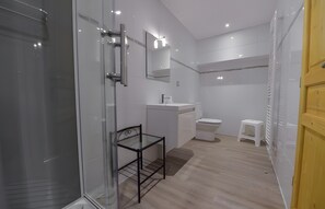 A modern bathroom with a glass shower enclosure, a white sink, a toilet, and a small stool. - Room 'Chambre Brésil' with Shared Garden and Wi-Fi (Rizaucourt-Buchey)