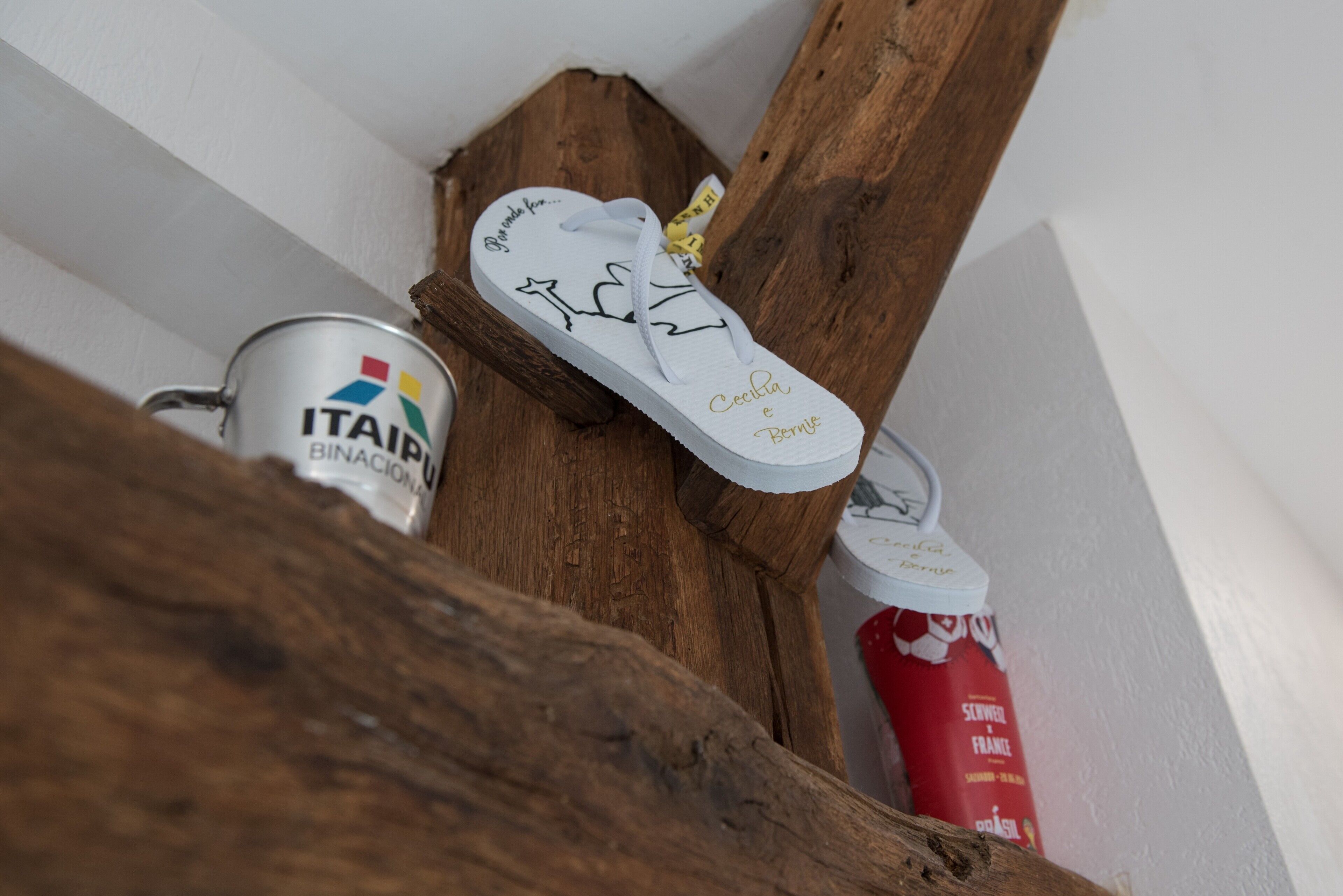 A pair of white sneakers with gold lettering on the sole, placed on a wooden surface.