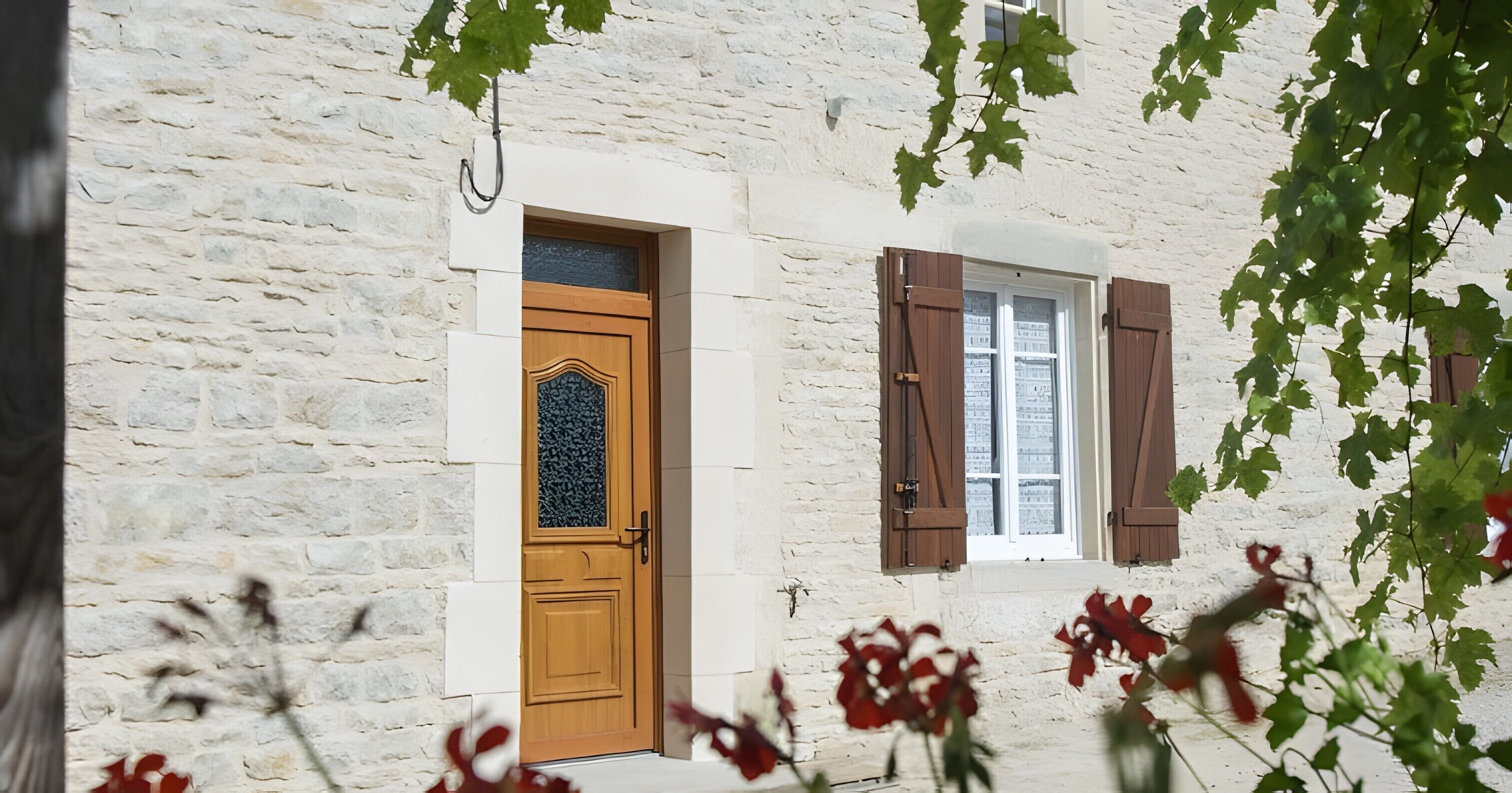 Un bâtiment en pierre avec une porte en bois et des volets aux fenêtres.