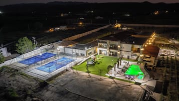 A residential property with a swimming pool, a tennis court, and a landscaped garden.