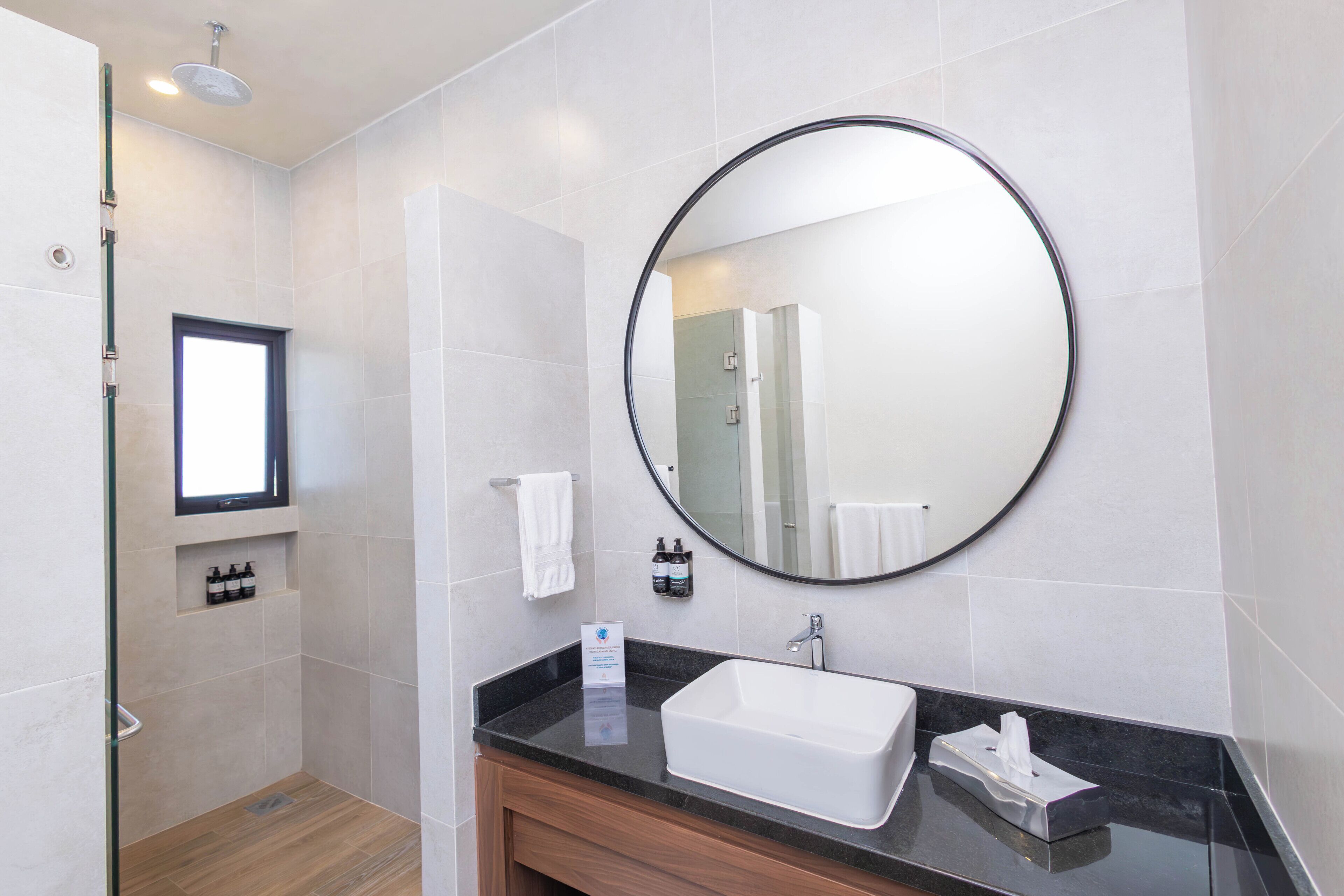 Un baño moderno con un espejo grande, un lavabo y una zona de ducha.