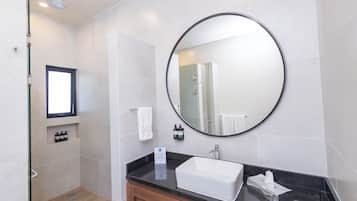 Un baño moderno con un espejo grande, un lavabo y una zona de ducha.