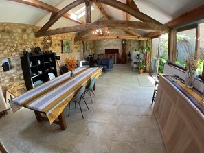 A spacious room with a long table, stone walls, wooden beams, and a fireplace.