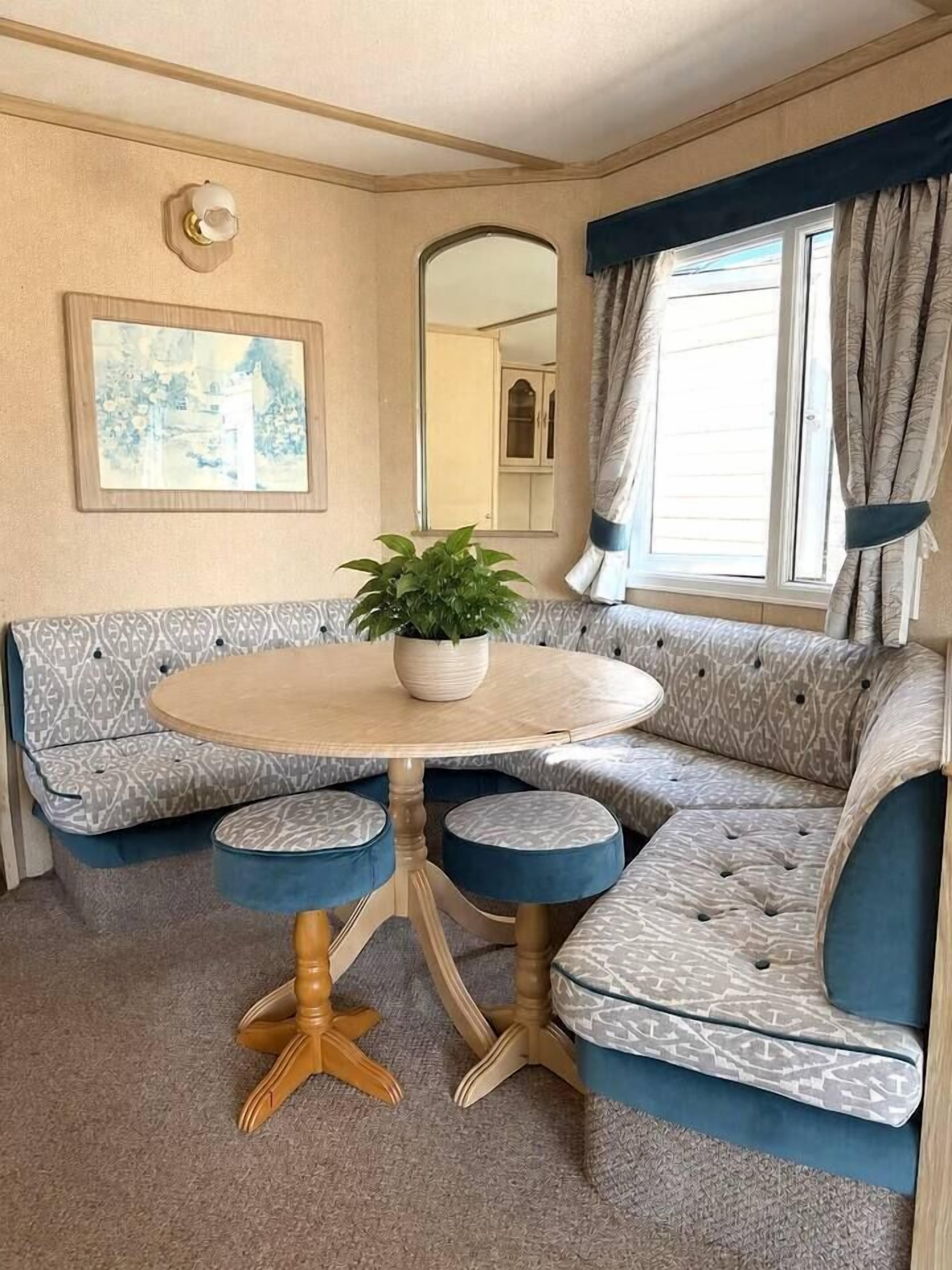 A cozy seating area with a round table, cushioned benches, and a potted plant.