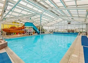 An indoor swimming pool with a slide and diving platforms.