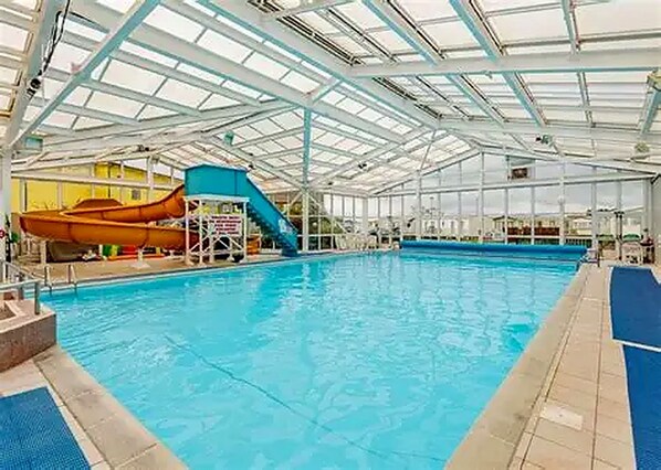 An indoor swimming pool with a slide and diving platforms.