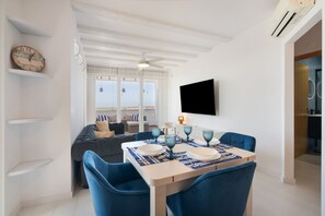 A dining area with a table set for four, a sofa, and a television mounted on the wall.