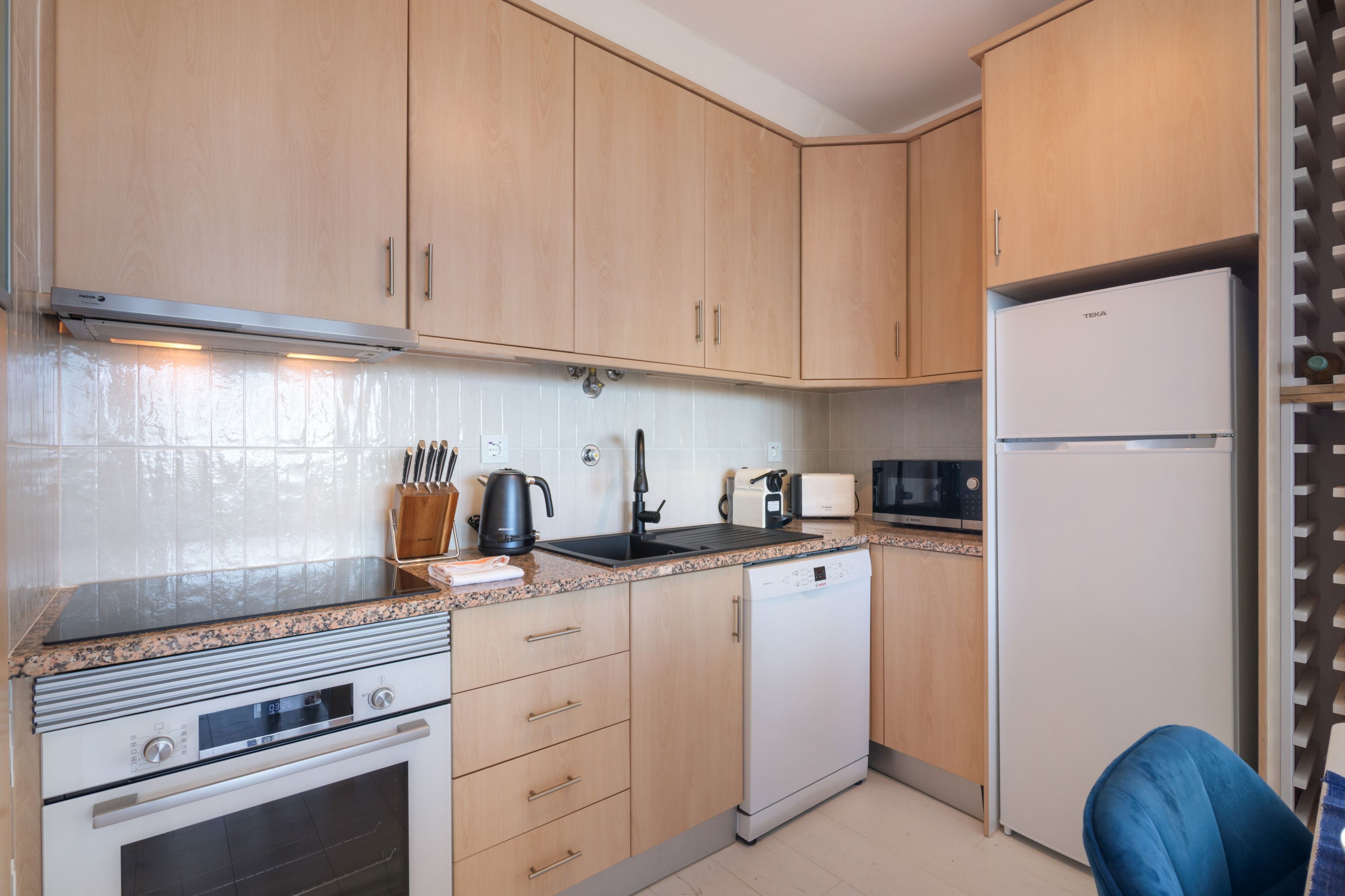 A compact kitchen with wooden cabinets, a built-in oven, a microwave, and a refrigerator.