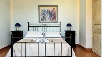 A single bed with a metal frame, two bedside tables with lamps, and a framed painting on the wall.