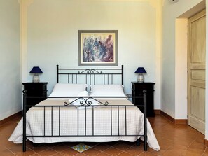 Ein Einzelbett mit Metallgestell, zwei Nachttische mit Lampen und ein gerahmtes Bild an der Wand.