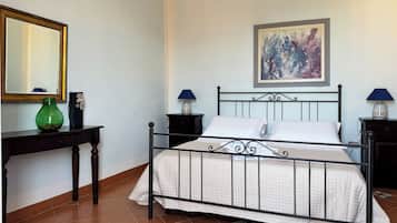 A bedroom with a bed, a bedside table, a lamp, a mirror, and a painting on the wall.