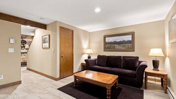 A living room with a wooden coffee table, a dark-colored sofa, and two lamps on side tables.