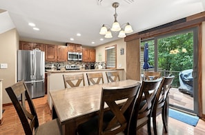 A kitchen with wooden cabinets, a stainless steel refrigerator, a microwave, and a dining area with a wooden table and chairs.