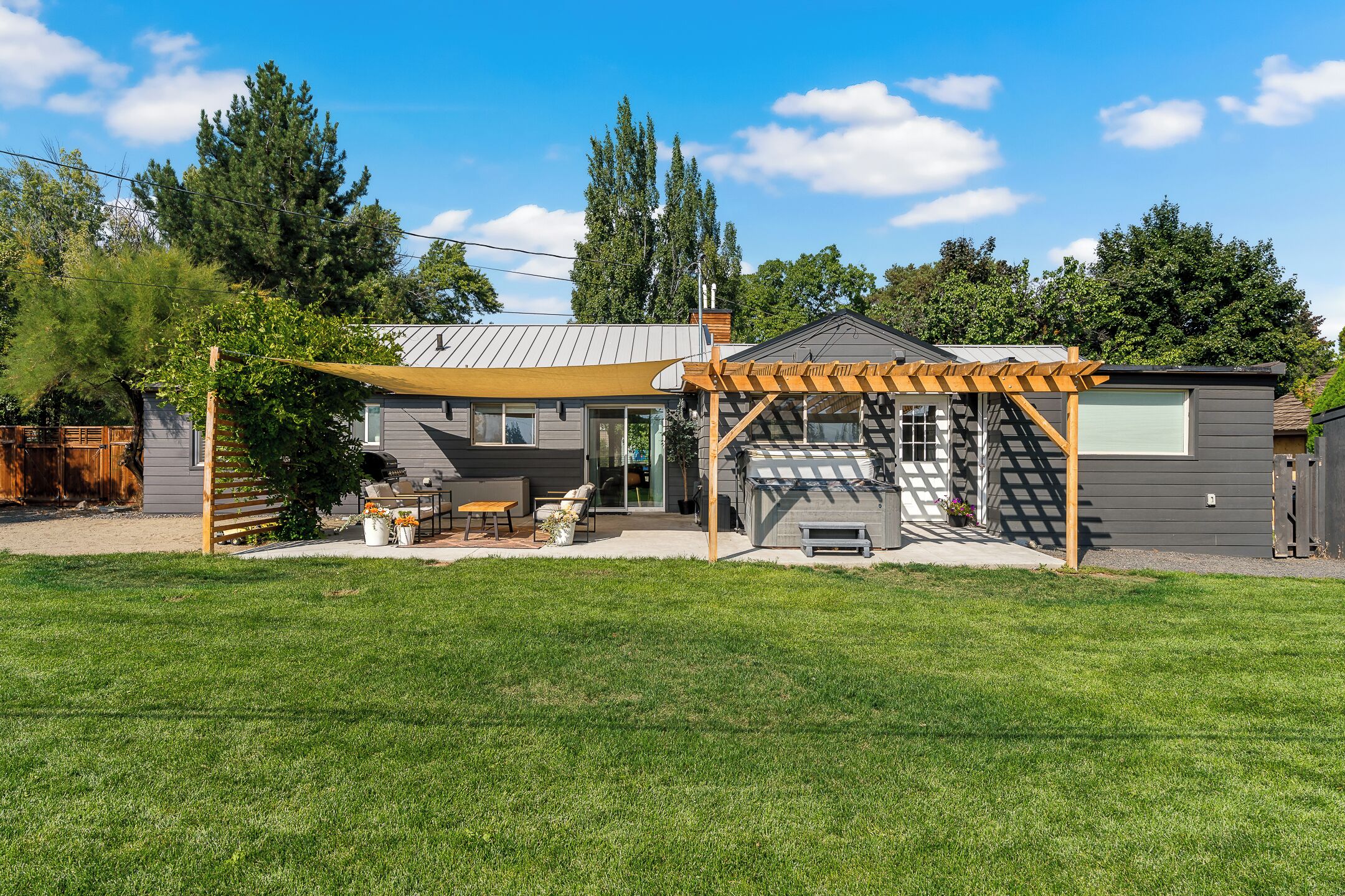 A residential property with a covered patio, outdoor seating, and a barbecue area.