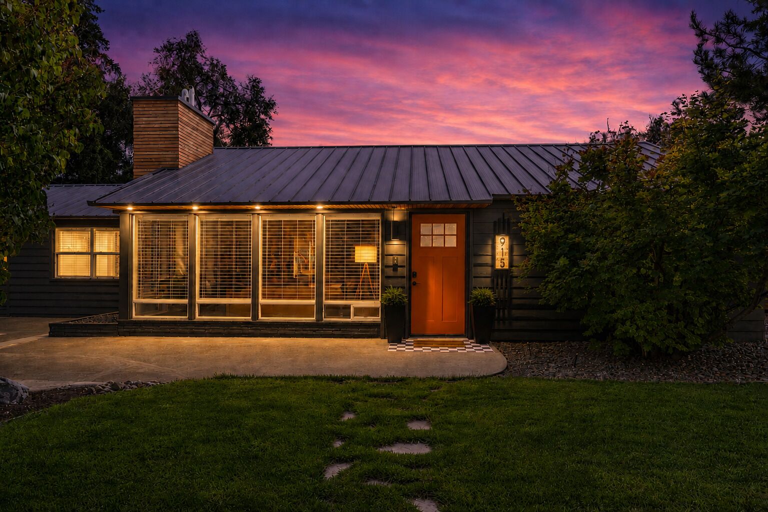 A house with a dark roof, a wooden exterior, and a well-lit front entrance.