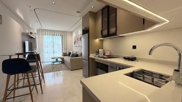 Una cocina moderna con lavavajillas integrado, un lavamanos de acero inoxidable y un comedor con mesa y sillas de vidrio.