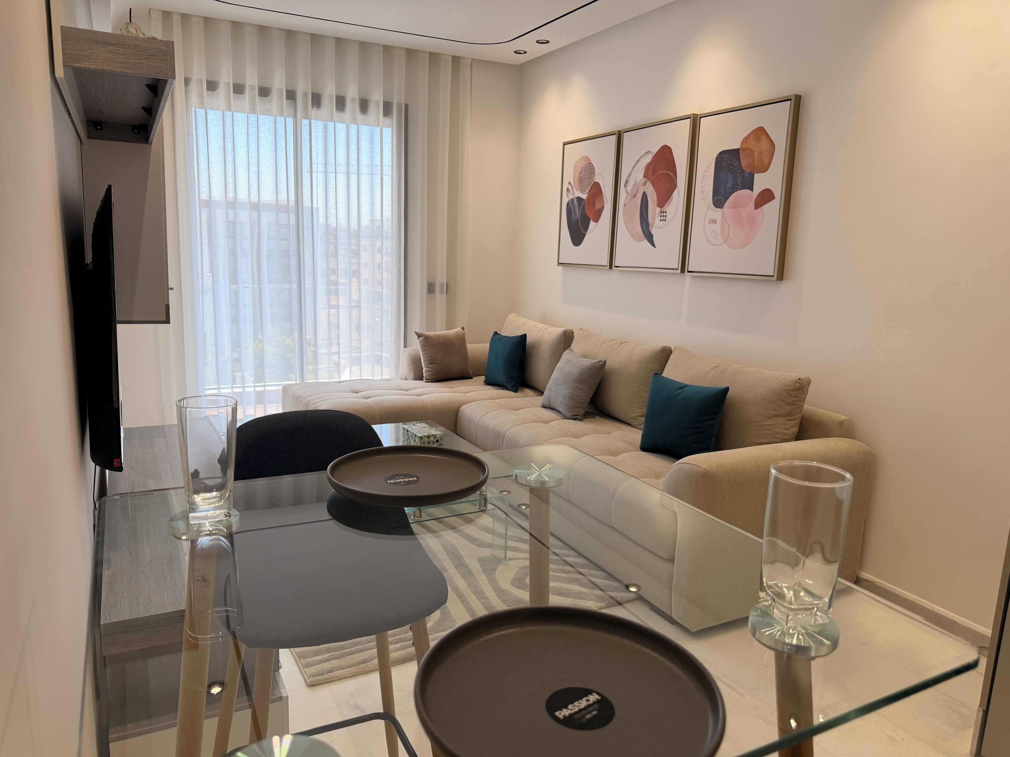A modern living room with a sofa, a glass coffee table, and a flat-screen TV.