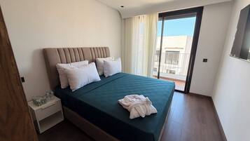 Habitación de hotel con cama, mesita de noche, bata y vistas al exterior.