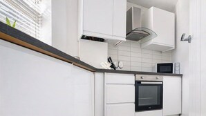 Cocina moderna con armarios blancos, horno integrado y microondas.
