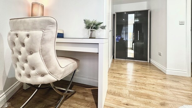 Un interior moderno con un sillón capitonado, un escritorio con lámpara y suelo de madera.