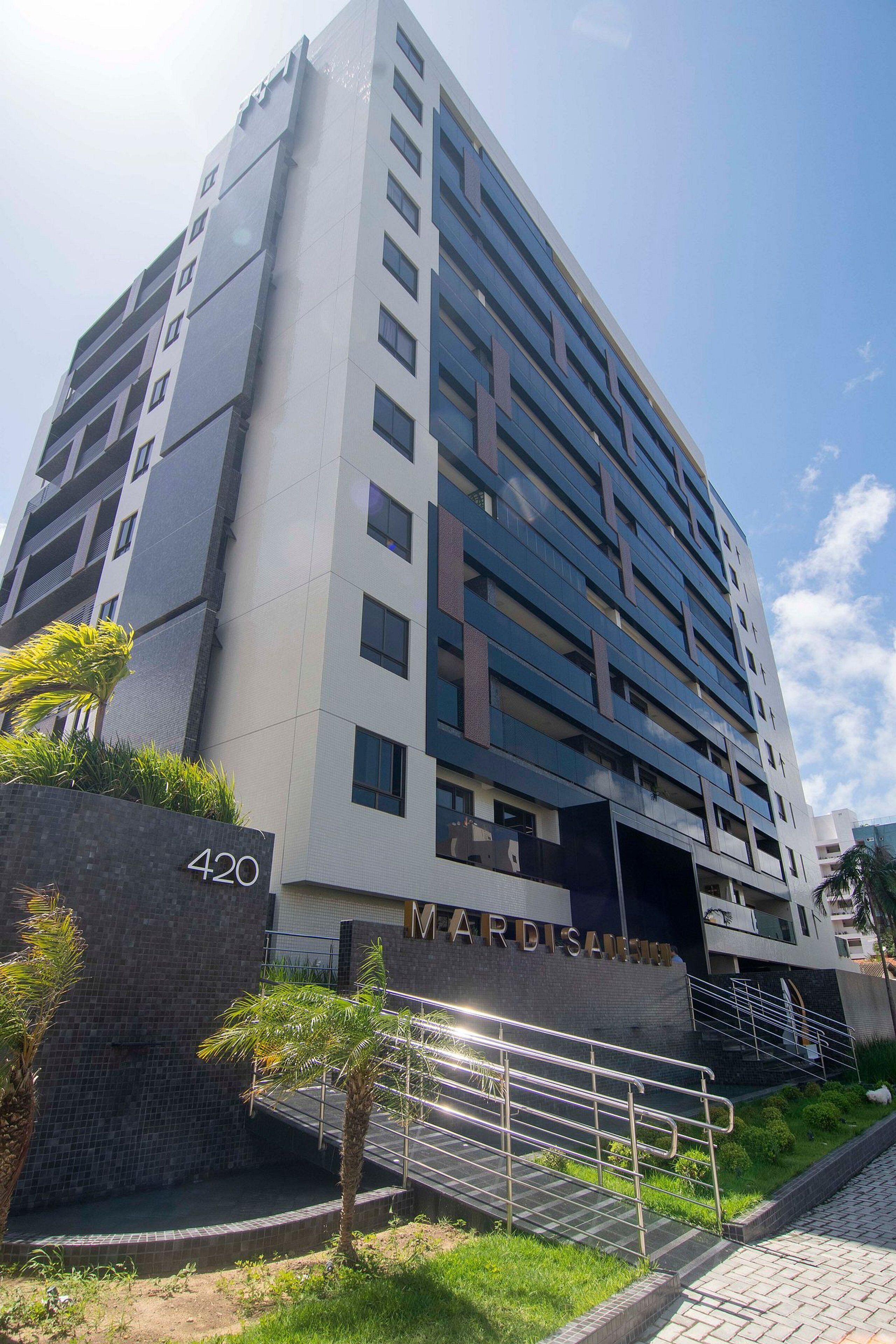 A multi-story building with a modern architectural design, featuring a prominent entrance with a glass facade and a sign that reads 'MARDIS DESIGN'.