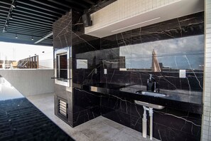 Ein modernes Badezimmer mit schwarzen Marmorarbeitsplatten, einem Waschbecken und einem Spiegel.