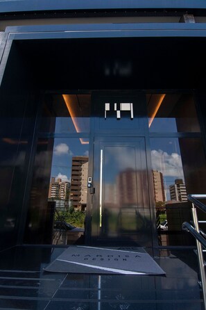 A modern building entrance with a glass door, a keypad lock, and a ramp for accessibility. - Mardisa Design Cabo Branco  (João Pessoa)