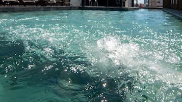 Ein Swimmingpool mit klarem Wasser, ein überdachter Sitzbereich und ein Gebäude mit der Aufschrift 'GARDEN GR'.