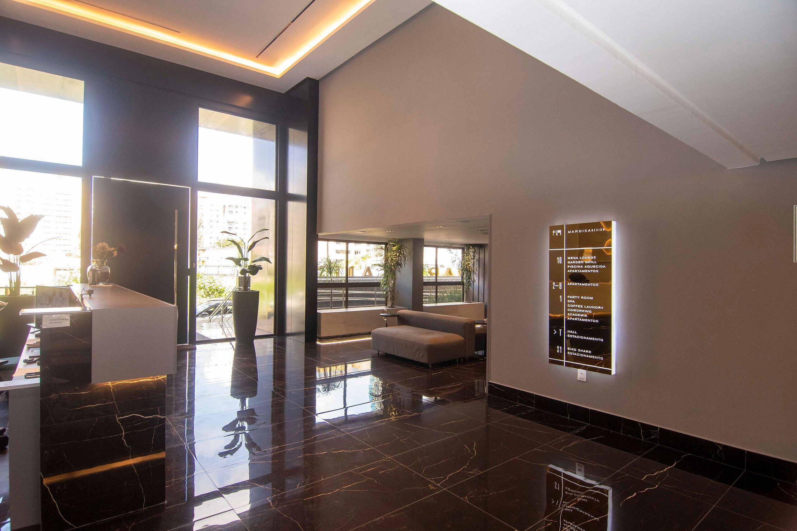 A modern lobby with a reception desk, seating area, and a wall-mounted directory.