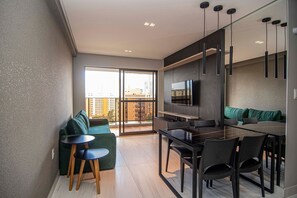 A modern apartment with a dining area, a sofa, and a TV mounted on the wall. - Mardisa Design Cabo Branco  (João Pessoa)