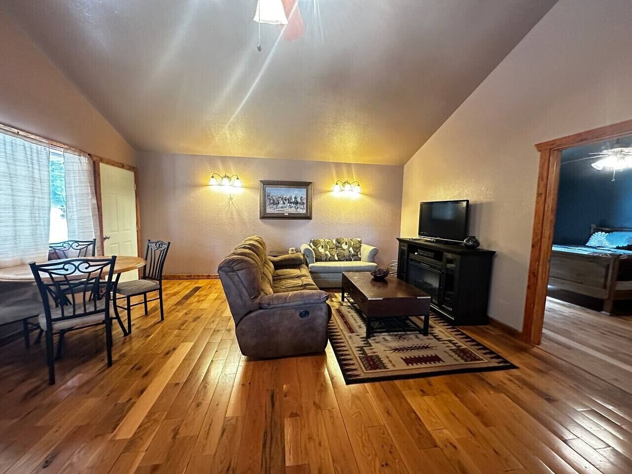 Una sala de estar con un sofá, sillas, una mesa de centro y un televisor.