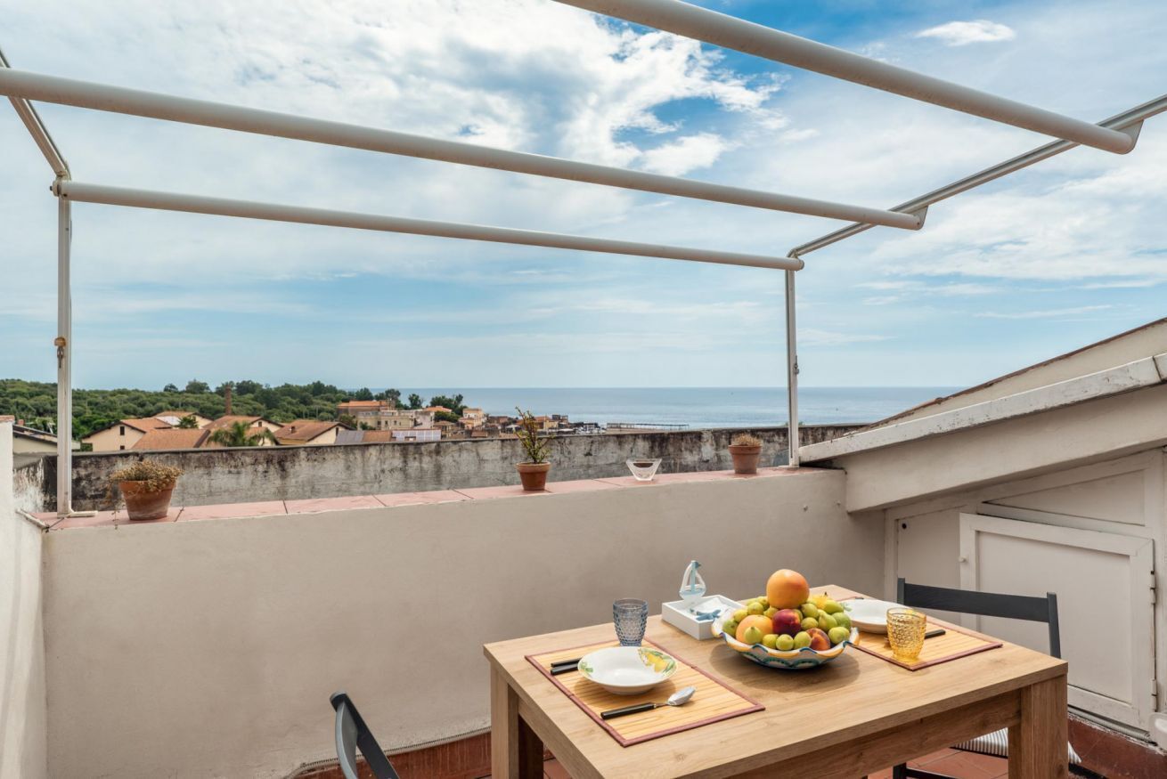 Un balcón con una mesa dispuesta para comer, con vista a un pueblo costero.