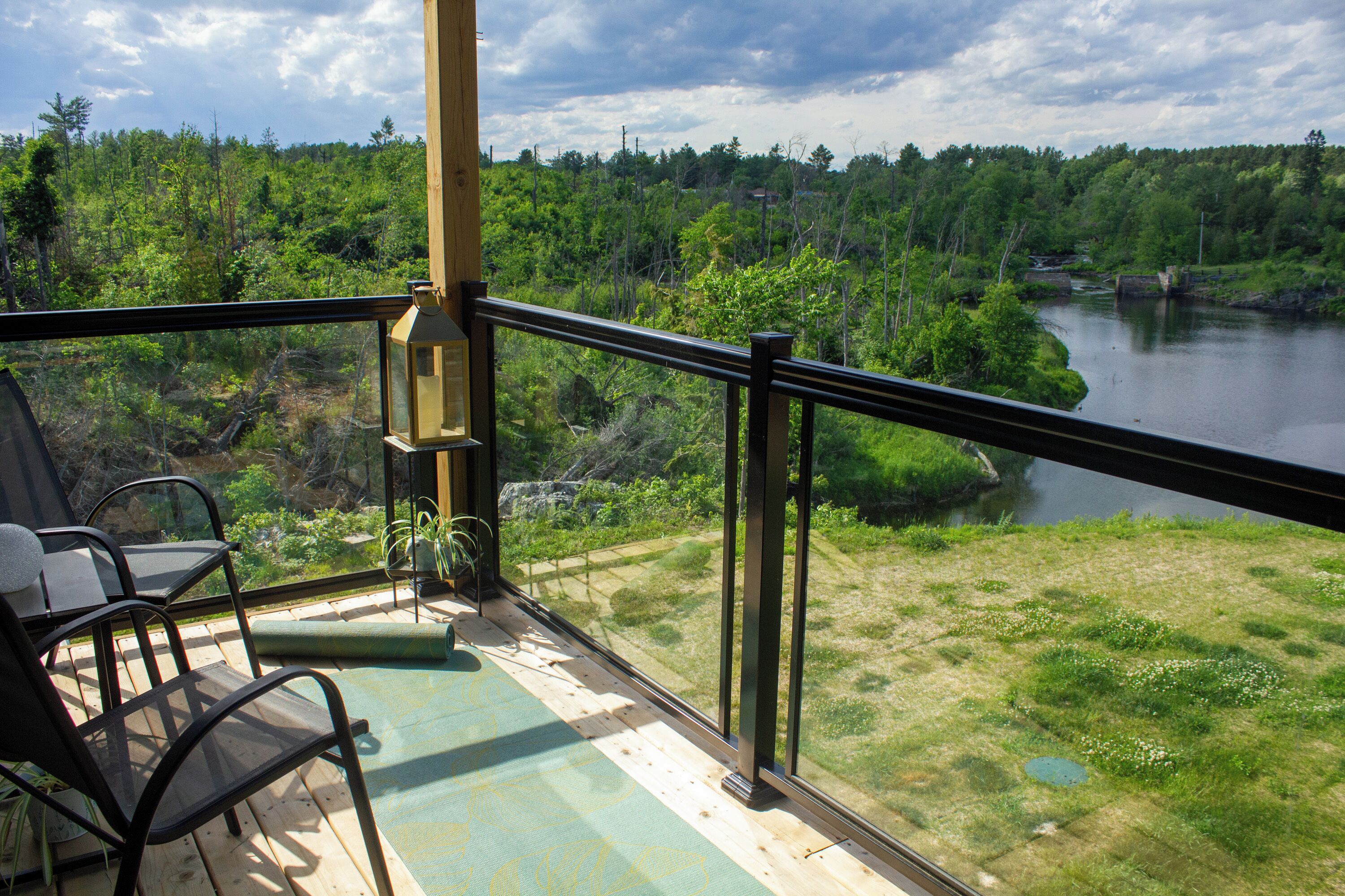 A balcony with a view of a river and forest.