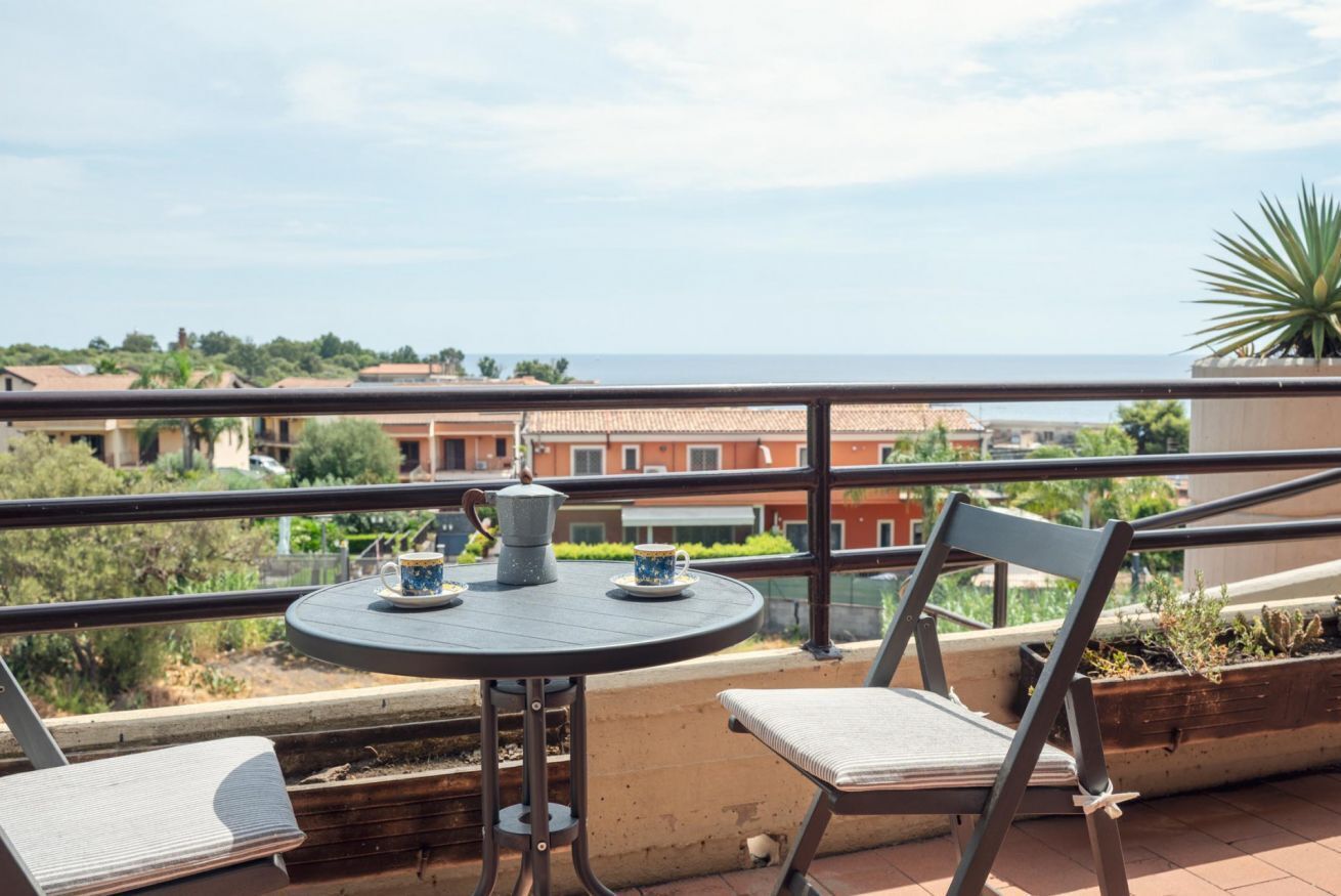Un balcón con mesa y sillas, con vista al mar.