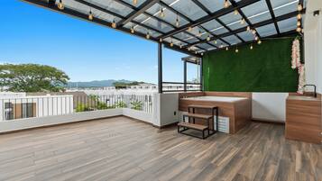 A balcony with a wooden floor, a green wall, and a bathtub.