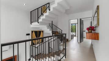 Una escalera moderna con barandal negro, paredes blancas y suelo de madera.
