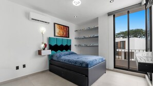 Un dormitorio moderno con cama, aire acondicionado de pared, luz de techo y un gran ventanal con vistas al exterior.