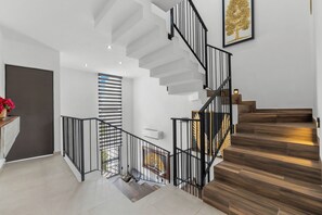 Una escalera moderna con barandilla de metal negro, paredes blancas y peldaños de madera.