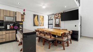Una cocina moderna con comedor, que cuenta con una isla grande, armarios de madera y un televisor de pantalla plana montado en la pared.